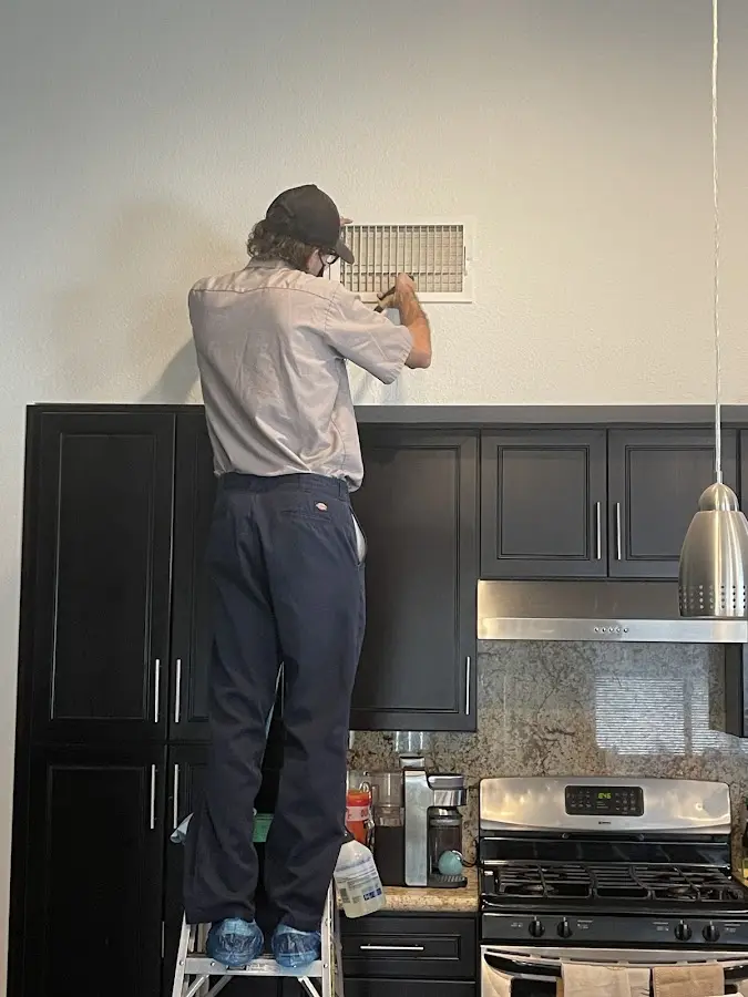 Technician inspecting an air vent during HVAC service in Orrville